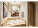 A relaxing bathtub with mosaic details sits below a window and a modern chandelier at 42171 N Saguaro Forest Dr, Scottsdale, AZ 85262