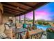 Inviting covered patio features a stone fireplace, comfortable seating, and a tranquil pool with vibrant flowerbeds, perfect for outdoor relaxation at 42171 N Saguaro Forest Dr, Scottsdale, AZ 85262