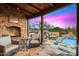 Charming outdoor patio with a stone fireplace and cozy seating, adjacent to a refreshing pool and surrounded by desert landscape at 42171 N Saguaro Forest Dr, Scottsdale, AZ 85262