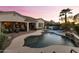 Aerial view of a serene backyard with a pool, spa, covered patio, and lush landscaping at twilight at 4320 E Ficus Way, Gilbert, AZ 85298