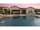 Inviting backyard pool featuring a flowing waterfall, lounge area, and charming home architecture at twilight at 4320 E Ficus Way, Gilbert, AZ 85298