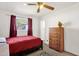 Bedroom with a red bedspread, matching curtains, and a wooden dresser at 5517 N 61St Ln, Glendale, AZ 85301