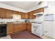 Functional kitchen with tiled floor, wooden cabinetry, and white appliances at 5517 N 61St Ln, Glendale, AZ 85301