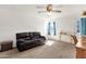 Comfortable living room with carpet, a ceiling fan, and a dark leather sofa at 5517 N 61St Ln, Glendale, AZ 85301