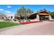 Inviting single-story property features a stone and wood portico, red flowers and mature landscaping against a clear blue sky at 7741 E Journey Ln, Scottsdale, AZ 85255