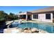 Beautiful backyard pool with rock features, lounge chairs, and outdoor patio at 7741 E Journey Ln, Scottsdale, AZ 85255