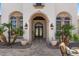 Close up on front entrance with a decorative door, arched windows, and well-manicured landscaping in the front at 11319 E Elmhurst Dr, Chandler, AZ 85249