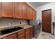 Laundry room featuring wooden cabinetry, a black sink, and modern washer and dryer at 11319 E Elmhurst Dr, Chandler, AZ 85249