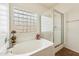 Bright bathroom featuring a soaking tub, separate glass shower, and block window at 11564 W Harrison St, Avondale, AZ 85323