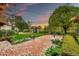 Expansive backyard boasts lush green lawn, vibrant flowerbeds, mature trees, and a charming wooden pergola for outdoor relaxation at 12 E Oakwood Hills Dr, Chandler, AZ 85248