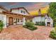 Inviting home exterior features a brick driveway, manicured landscaping, and a cozy outdoor fireplace, perfect for evening gatherings at 12 E Oakwood Hills Dr, Chandler, AZ 85248