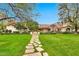 Elegant home showcasing a well-manicured lawn, mature trees, and a charming stone pathway to the entrance at 12 E Oakwood Hills Dr, Chandler, AZ 85248