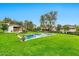 A swimming pool in a large yard, surrounded by green grass and mature trees, with the house in the background at 12 E Oakwood Hills Dr, Chandler, AZ 85248