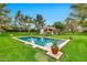 Backyard view of a sparkling pool and lush green lawn surrounded by mature trees on a sunny day at 12 E Oakwood Hills Dr, Chandler, AZ 85248