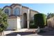 Inviting two-story stucco home featuring a two car garage, red rock landscaping and arched windows at 1417 W Lake Mirage Ct, Gilbert, AZ 85233