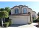 Inviting two-story stucco home featuring a two car garage, lush bushes and arched windows at 1417 W Lake Mirage Ct, Gilbert, AZ 85233