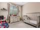 Neutral bedroom featuring a dresser, crib, and window with natural light at 16573 W Alameda Rd, Surprise, AZ 85387