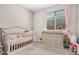 Charming Bedroom with a crib, dresser, and pink curtains with a bright window at 16573 W Alameda Rd, Surprise, AZ 85387