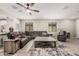 Spacious living room featuring wood tile floors, a ceiling fan, and a comfortable leather sectional sofa at 16573 W Alameda Rd, Surprise, AZ 85387