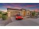Inviting home with an attached two-car garage, beautiful desert landscaping, and bright red sports car at 187 E Santa Lucia Ln, Queen Creek, AZ 85140