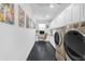 Modern laundry room with white cabinets, black tiled floors, a built-in desk, and sleek washer and dryer units at 187 E Santa Lucia Ln, Queen Creek, AZ 85140
