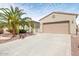 Beige single-story home featuring a two-car garage, concrete driveway, and mature palm tree in landscaped front yard at 21026 N Circle Cliffs Dr, Surprise, AZ 85387