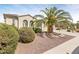Tan single-story home showing manicured yard with mature palm tree and other trees/shrubs at 21026 N Circle Cliffs Dr, Surprise, AZ 85387