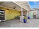 Covered patio boasts brick flooring, ceiling fans, colorful potted plants, and dining and seating areas at 2140 W Mitchell Dr, Phoenix, AZ 85015