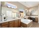 Bright bathroom with large jacuzzi-style tub, tile accents, vanity, and picture window at 23108 N Pedregosa Dr, Sun City West, AZ 85375