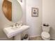 Elegant powder room with a pedestal sink, round mirror, and tile flooring at 36190 N Creek View Ln, Cave Creek, AZ 85331