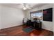 A well-lit bedroom featuring hardwood floors, a ceiling fan, a window and a dark wooden desk at 3875 E Juanita Ave, Gilbert, AZ 85234
