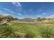 Expansive backyard view featuring a lush green lawn, tranquil pond, and picturesque mountain backdrop at 4013 N Founder Cir, Buckeye, AZ 85396