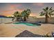 Kidney-shaped pool with large concrete decking, palm trees and block wall at 4013 N Founder Cir, Buckeye, AZ 85396
