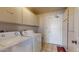 Functional laundry room with a washer, dryer, storage cabinets, and a tiled floor at 4014 W Anderson Dr, Glendale, AZ 85308