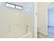 Bright, tiled bathroom with a bathtub, window, and organized shelving unit at 516 N Emery --, Mesa, AZ 85207