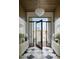 Elegant foyer with a black and white checkered floor, a modern chandelier, and a view of the front yard at 6147 E Desert Cove Ave, Scottsdale, AZ 85254