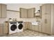 Well-organized laundry room with a farmhouse sink, modern washer and dryer, and ample cabinet space at 6147 E Desert Cove Ave, Scottsdale, AZ 85254