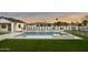 A beautiful backyard pool with a jacuzzi, surrounded by greenery, is nestled among other modern homes at 6147 E Desert Cove Ave, Scottsdale, AZ 85254
