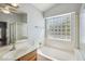 Bathroom showcases a soaking tub with glass block window, a vanity with sink and glass shower stall at 6659 W Oraibi Dr, Glendale, AZ 85308