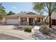 Charming single-story home features a tile roof, landscaped front yard, and inviting covered porch with stone accents at 6659 W Oraibi Dr, Glendale, AZ 85308