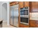 Stainless steel refrigerator and double ovens with wooden cabinetry at 7201 E Sandia Cir, Mesa, AZ 85207