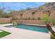 Backyard pool area surrounded by desert landscaping with a retaining wall for privacy at 7201 E Sandia Cir, Mesa, AZ 85207
