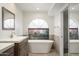 Modern bathroom features a freestanding tub under a large arched window at 7245 E Buena Terra Way, Scottsdale, AZ 85250