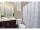 Neutral bathroom features a sink with a brown vanity and a white toilet and shower curtain at 811 E Gold Dust Way, San Tan Valley, AZ 85143