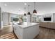 Kitchen island with marble countertop and barstool seating, illuminated by pendant lights, overlooking a bright and spacious living area at 10511 E Diffraction Ave, Mesa, AZ 85212