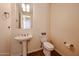 A powder room with a pedestal sink, tile floors, and a large mirror offers a convenient space for guests at 12439 W Yellow Bird Ln, Peoria, AZ 85383