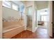 Bathroom featuring a soaking tub, glass-enclosed shower, and decorative coastal-themed accents at 12439 W Yellow Bird Ln, Peoria, AZ 85383