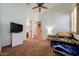 This light-filled bedroom offers a ceiling fan, tv, and an attached bathroom at 12439 W Yellow Bird Ln, Peoria, AZ 85383