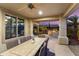 Inviting covered patio with dining table, outdoor kitchen, and beautifully landscaped backyard at 13065 W Lucia Dr, Peoria, AZ 85383