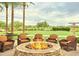 Outdoor seating area featuring a stone fire pit surrounded by lush landscaping and mountain views at 13065 W Lucia Dr, Peoria, AZ 85383